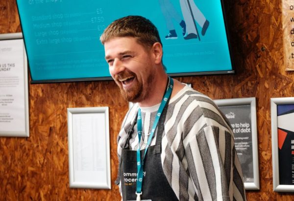 A Grocery team member at Harpurhey Community Grocery laughs with a customer.