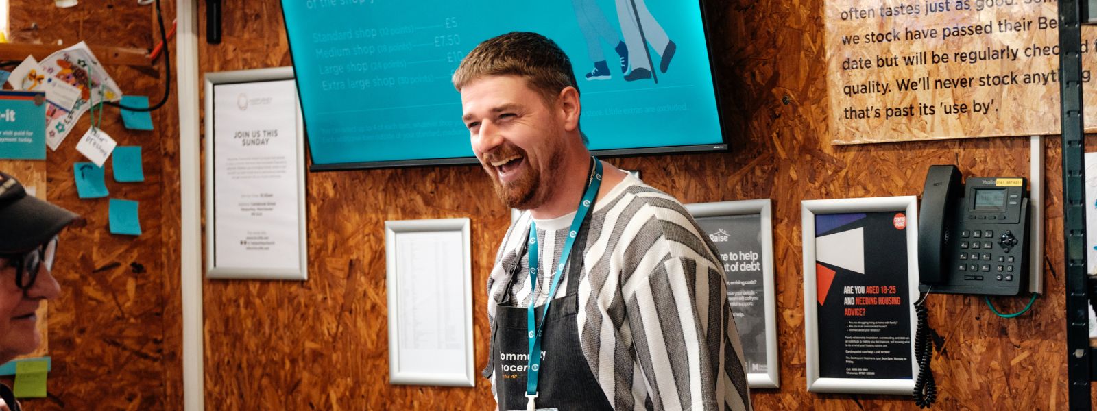 A Grocery team member at Harpurhey Community Grocery laughs with a customer.